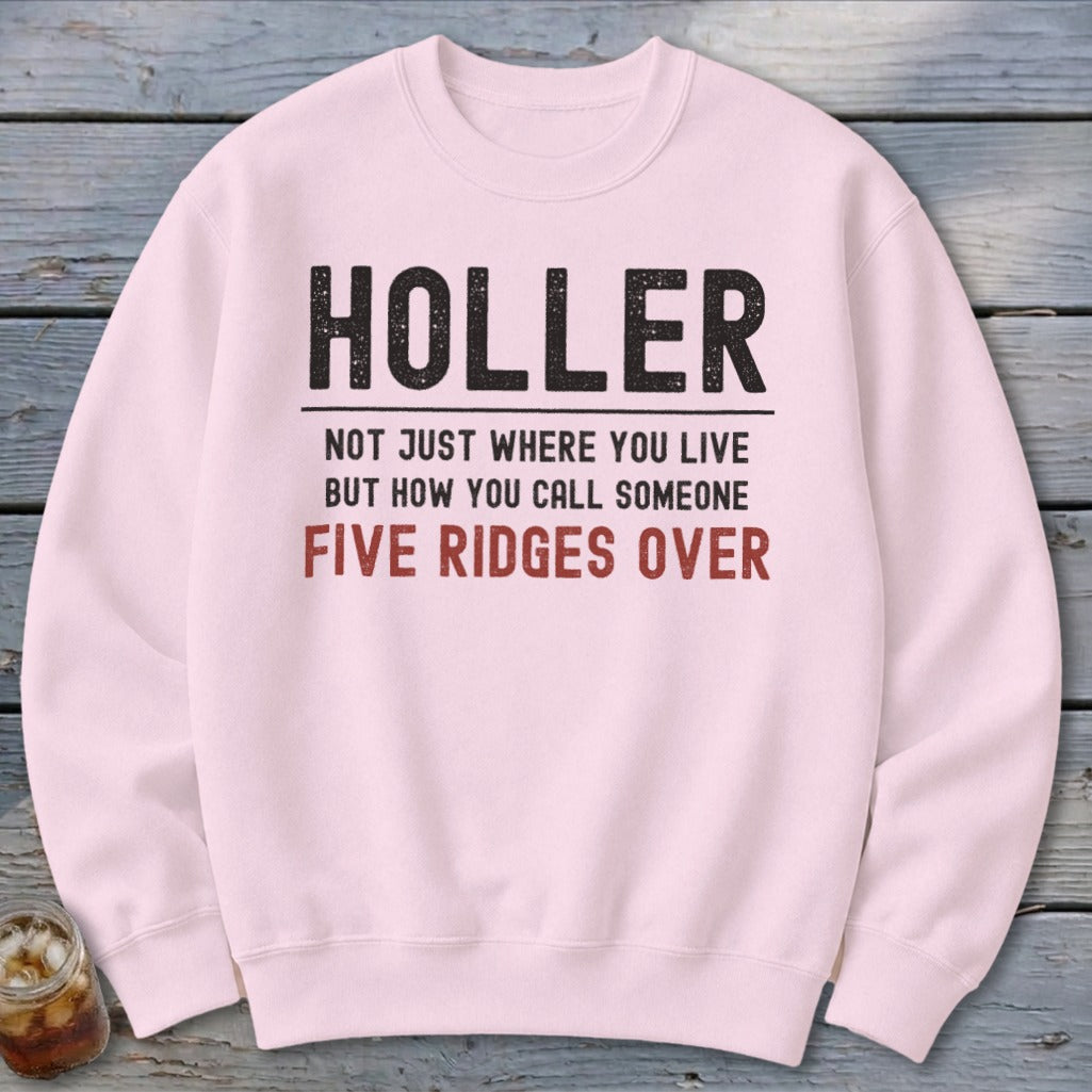 Light pink sweatshirt with text: "HOLLER NOT JUST WHERE YOU LIVE BUT HOW YOU CALL SOMEONE FIVE RIDGES OVER".
