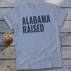 Light blue t-shirt with dark blue text "ALABAMA RAISED" and a mason jar with iced tea.