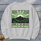 Light gray crewneck sweatshirt featuring a green mountain graphic and the text Born in the Holler Raised on the Ridge.