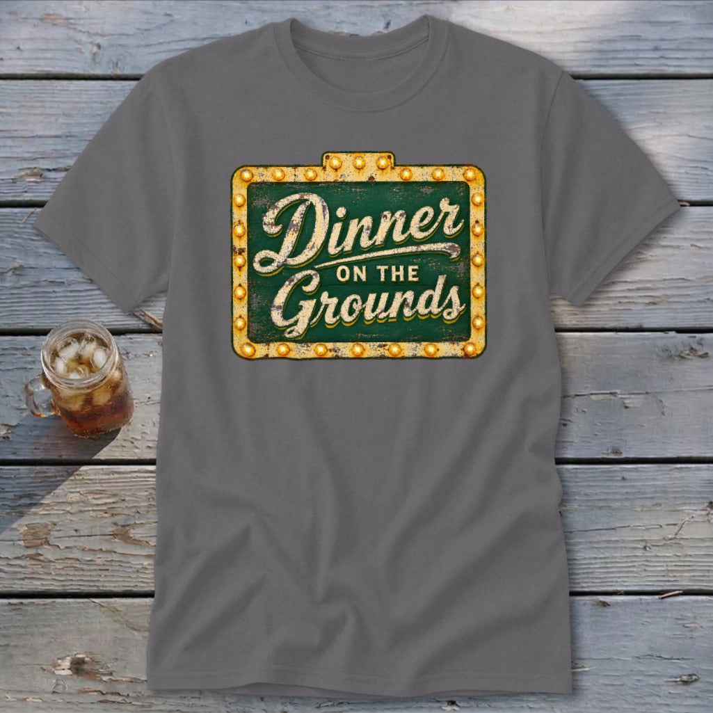 Charcoal gray crewneck t-shirt featuring a green vintage-style marquee sign graphic that reads "Dinner on the Grounds".
