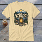 Light yellow t-shirt with graphic of lantern, mountains, and text "Always Leave the Light On Come On In".