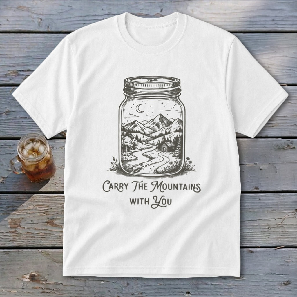 A white t-shirt featuring a mason jar illustration filled with a mountain landscape and text reading Carry The Mountains With You.