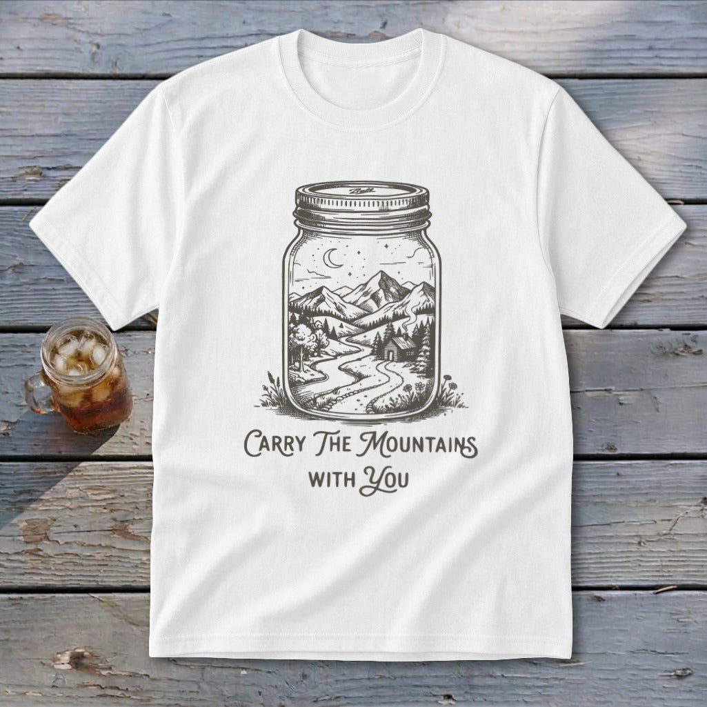 A white t-shirt featuring a mason jar illustration filled with a mountain landscape and text reading Carry The Mountains With You.