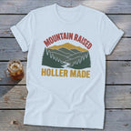 White t-shirt with a vintage mountain landscape graphic and the text Mountain Raised Holler Made.