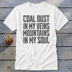 A white t-shirt featuring the distressed gray text Coal Dust In My Veins Mountains In My Soul.