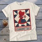Cream t-shirt with "Sunbonnet Sue" graphic of a girl in a quilt block pattern.