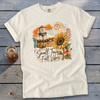 Cream t-shirt with a graphic of a water tower, sunflower, and "Small Town Fall Vibes" text.