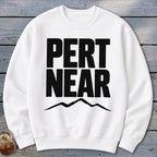 A white crewneck sweatshirt featuring the black text PERT NEAR above a mountain range graphic.