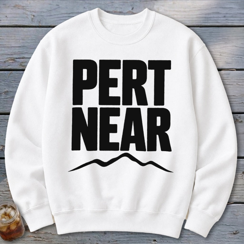A white crewneck sweatshirt featuring the black text PERT NEAR above a mountain range graphic.