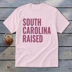 Pink t-shirt with "SOUTH CAROLINA RAISED" text in maroon.