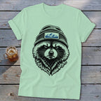 Light green t-shirt with a black illustration of a raccoon wearing a beanie with a mountain patch.