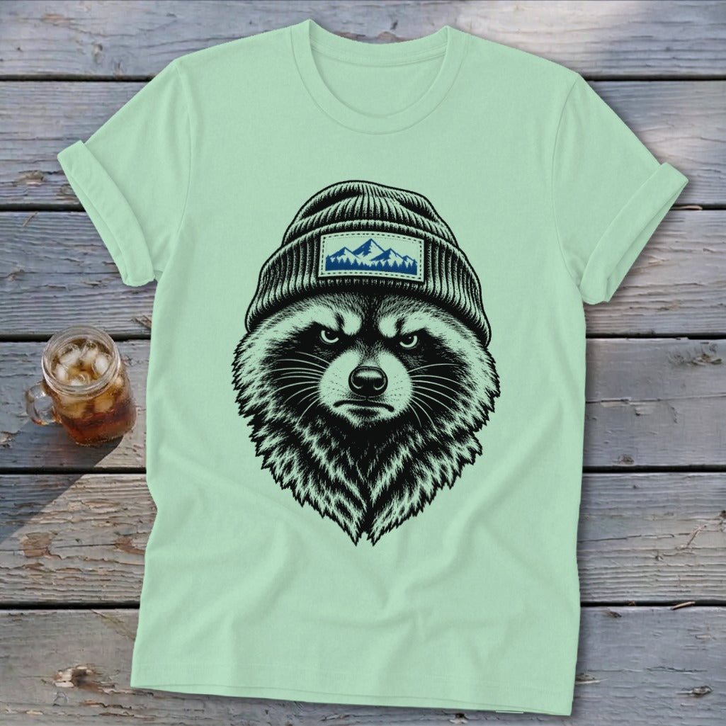 Light green t-shirt with a black illustration of a raccoon wearing a beanie with a mountain patch.