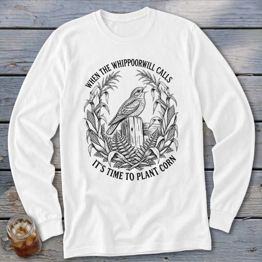 A white long-sleeve t-shirt with a black line art graphic of a bird, cornstalks, and text.