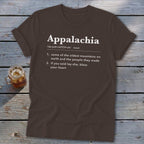Brown t-shirt featuring dictionary-style text defining Appalachia, laid flat on a rustic wooden surface.