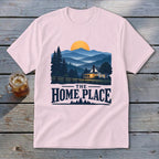 Pink t-shirt featuring a cabin in a mountain landscape with text "THE HOME PLACE".