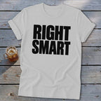 A grey crewneck t-shirt with black text that reads RIGHT SMART lying on a wooden table.