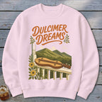 Pink sweatshirt with "Dulcimer Dreams" text and a dulcimer on a porch railing with mountains.