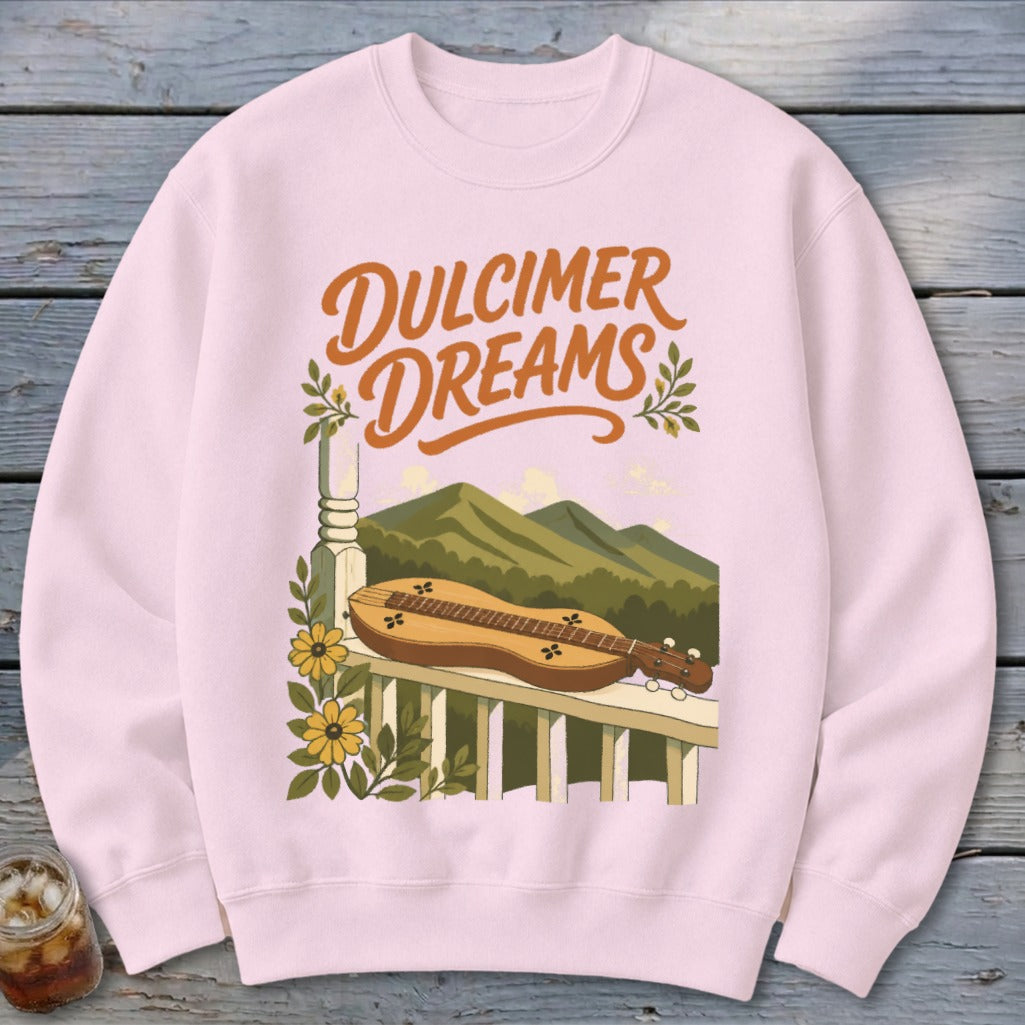 Pink sweatshirt with "Dulcimer Dreams" text and a dulcimer on a porch railing with mountains.