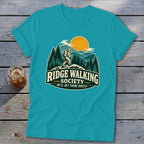 T-shirt graphic: hiker on ridge, mountains, sun, trees, "Ridge Walking Society" text.