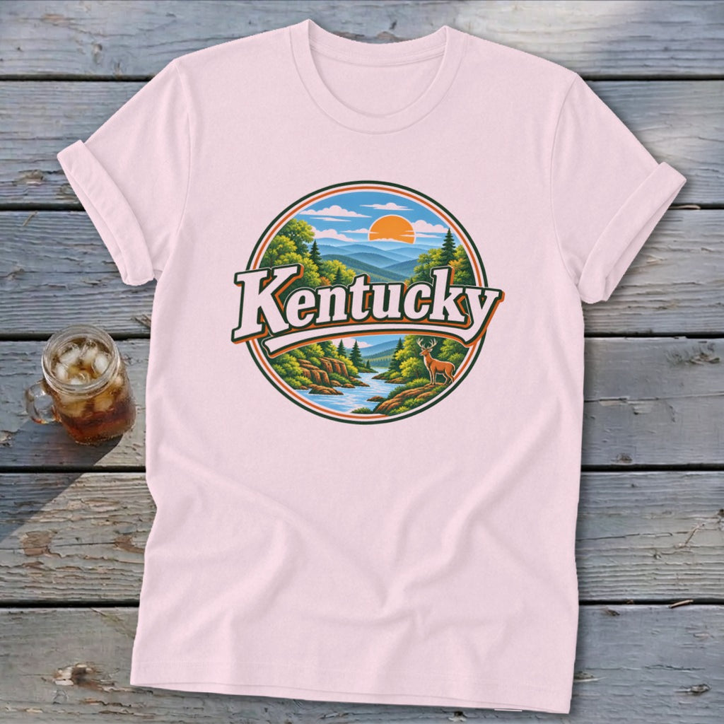 Pink t-shirt with a circular graphic featuring "Kentucky" text, mountains, river, trees, and a deer.