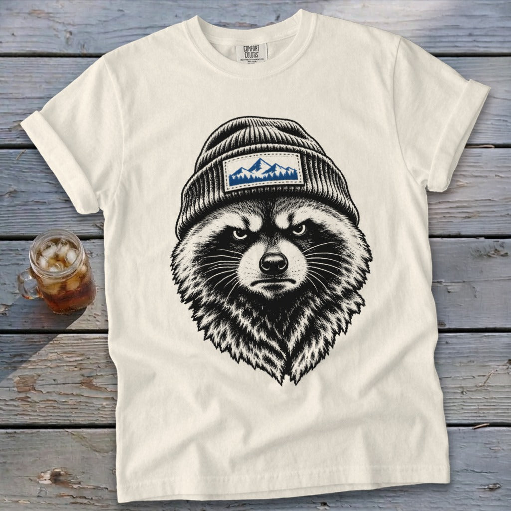 Cream t-shirt with a graphic of a raccoon wearing a beanie with mountains.