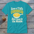 A turquoise t-shirt with the graphic text "Some of Y'all's Cornbread Ain't Done in the Middle."