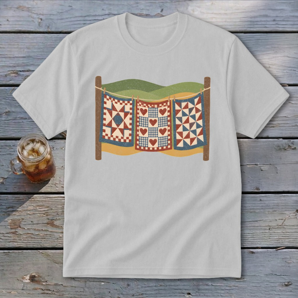 Light gray t-shirt featuring a graphic of three patchwork quilts hanging on a clothesline outdoors.