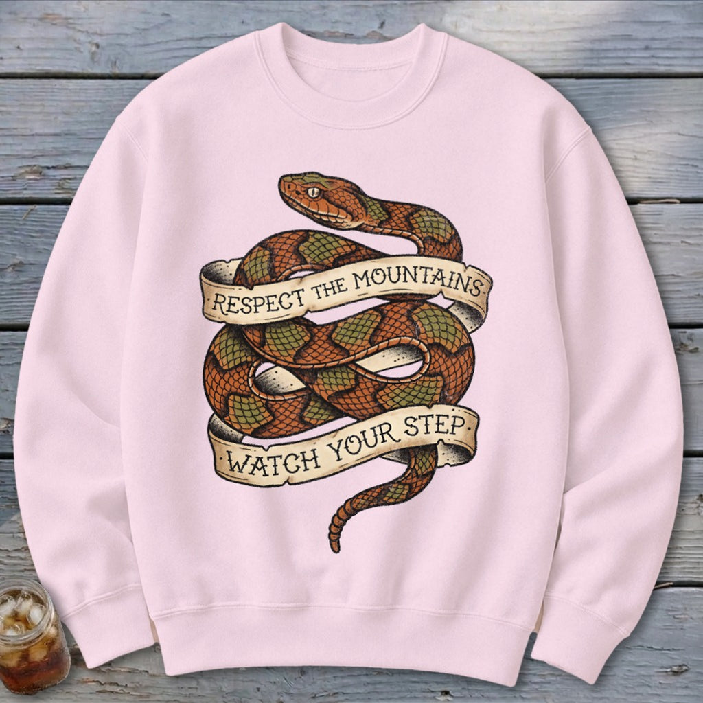 Pink sweatshirt with coiled snake design and text "Respect the mountains watch your step".