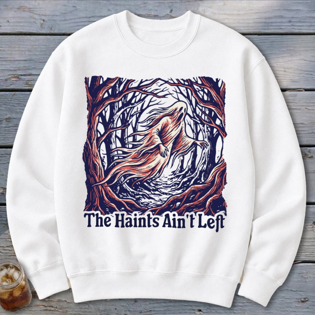 White sweatshirt with ghost in spooky forest graphic and text "The Haints Ain't Left".