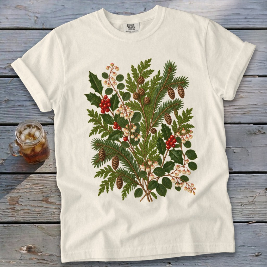 White t-shirt with a central botanical print of pine, holly, berries, and pinecones.
