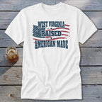 A white t-shirt featuring a distressed American flag and text that reads West Virginia Raised American Made.