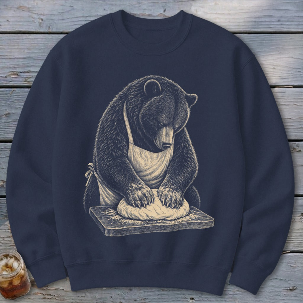 Bear in apron kneading dough on a wooden board, illustrated design on navy sweatshirt.