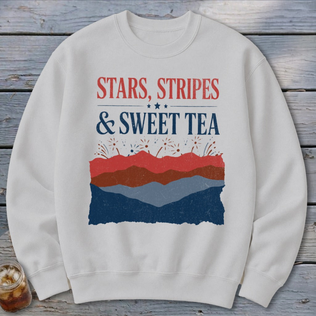 A cream-colored crewneck sweatshirt featuring the text STARS, STRIPES & SWEET TEA above a patriotic layered landscape design.
