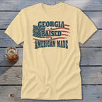 Cream t-shirt featuring a distressed American flag graphic with the text Georgia Raised American Made.