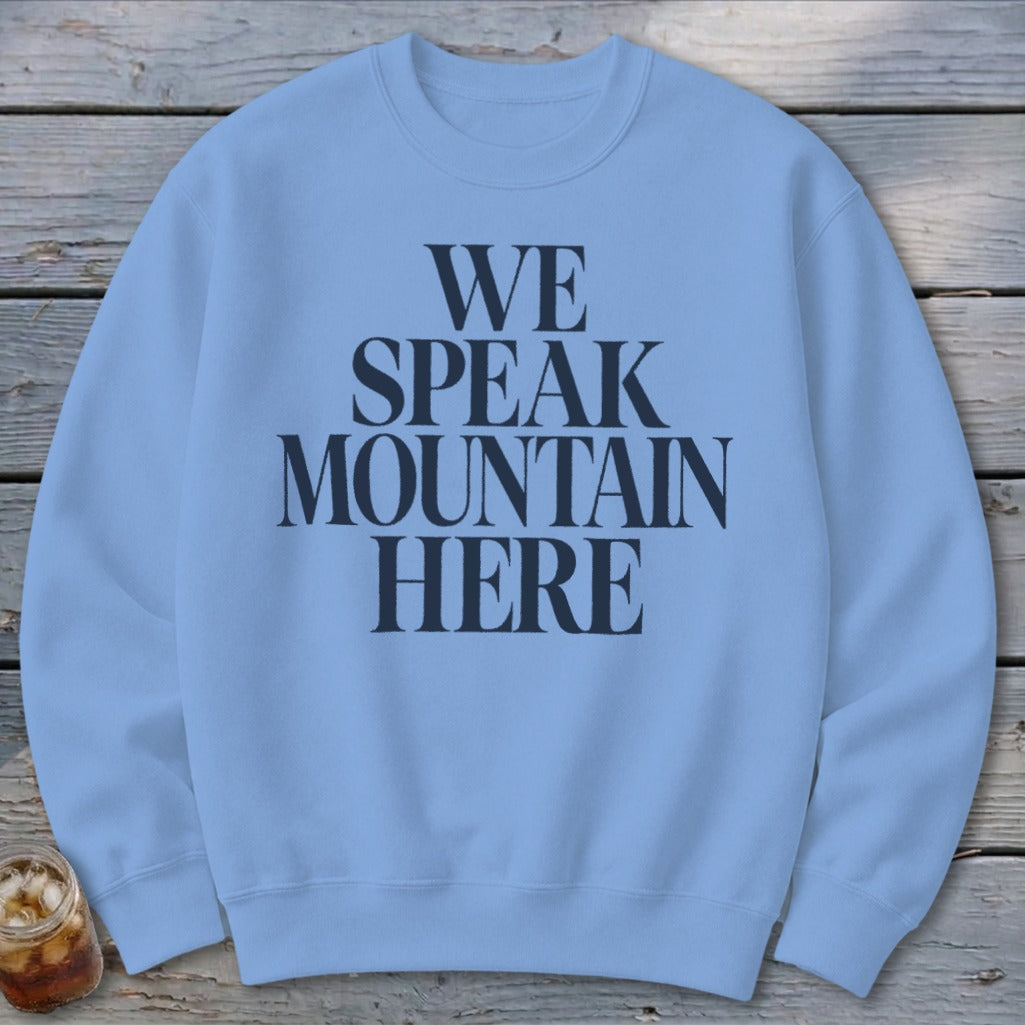 Light blue crewneck sweatshirt with "WE SPEAK MOUNTAIN HERE" text in dark blue.