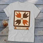 White t-shirt with a quilted "Turkey Track" design in brown and orange.