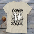 Cream t-shirt with "Barefoot on the Creek Bank" text and illustration of feet in water.