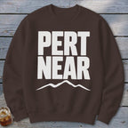 Brown crewneck sweatshirt with large white text reading PERT NEAR above a mountain outline.