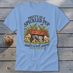 Blue t-shirt with a speckled puppy sleeping under a red wagon and text "Pretty as a speckled pup".