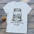 Light blue t-shirt featuring a mason jar graphic enclosing a mountain landscape and text reading Carry The Mountains With You.