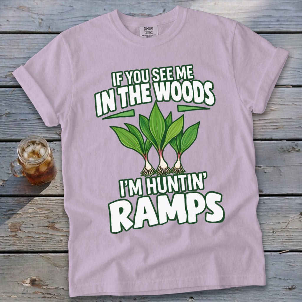A light purple t-shirt featuring green text reading IF YOU SEE ME IN THE WOODS I'M HUNTIN RAMPS above an illustration of three ramps plants.
