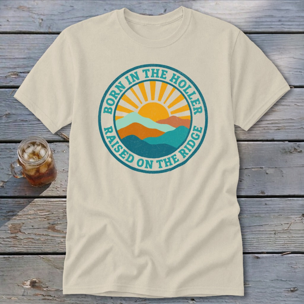 A beige t-shirt featuring a circular retro graphic with mountains, a sun, and text.