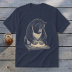 Bear wearing apron kneading dough on a wooden cutting board.