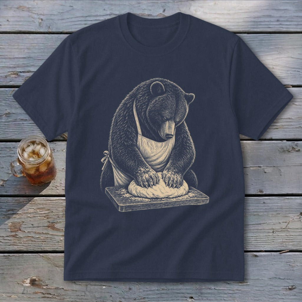 Bear wearing apron kneading dough on a wooden cutting board.