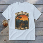 Light blue t-shirt with "The Porch Light Is Always On" cabin sunset graphic.