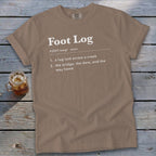 A brown t-shirt featuring dictionary definition text for the term Foot Log in white lettering.
