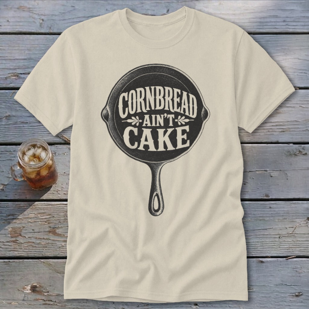 Cream t-shirt with black graphic of cast iron skillet and "Cornbread Ain't Cake" text.