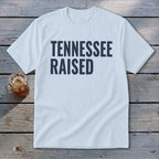 White t-shirt with navy blue text reading "TENNESSEE RAISED".