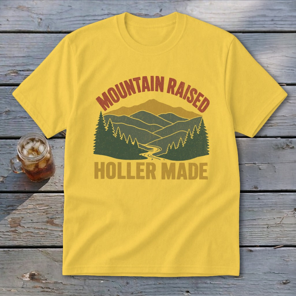 A yellow t-shirt featuring a retro mountain and pine tree graphic with the text Mountain Raised Holler Made.