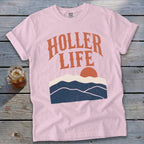 Pink t-shirt with "HOLLER LIFE" graphic and mountain sunset design.